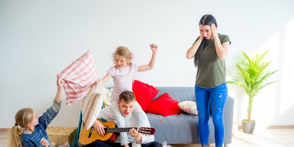 Kids playing and making a mess in a stylish living room with a grey sofa, scattered toys, and a playful, vibrant atmosphere.